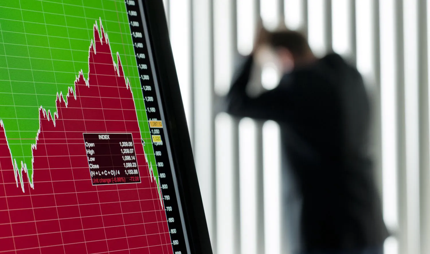 a plummeting stock screen on a computer monitor with a worried margin trader in the background leaning against a window