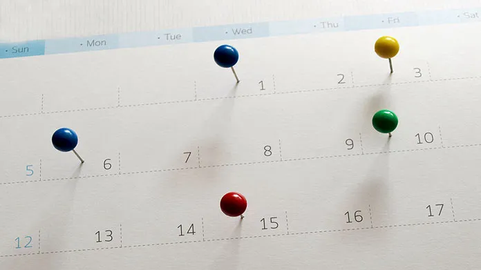 Calendar with colored push pins stuck into it